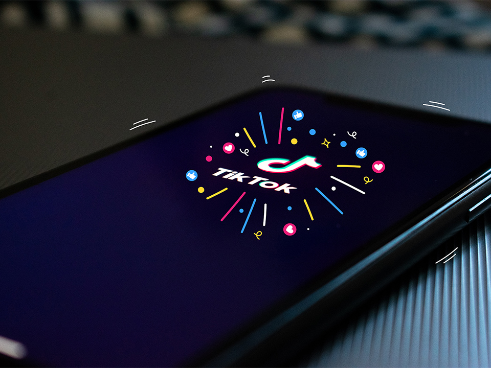 The TikTok logo on a phone screen, surrounded by colourful lines and emojis